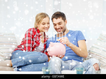 smiling couple with piggybank sitting on sofa Stock Photo