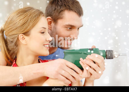 smiling couple drilling hole in wall at home Stock Photo