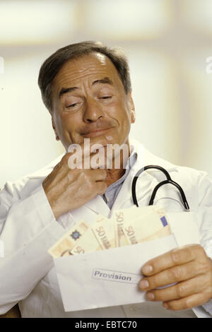 doctor holding an envelope with a commission paiment in hands contently smirking Stock Photo