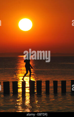 woman walking on groyne at sunset, Germany, Mecklenburg-Western Pomerania