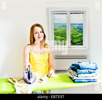 Happy young beautiful woman ironing clothes. Housework Stock Photo