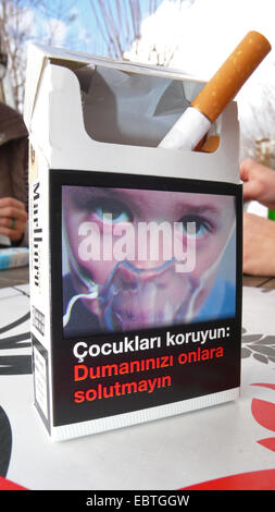 cigarette packet with the photo of a child wearing a respiratory mask standing on the table of a street cafe, Turkey Stock Photo