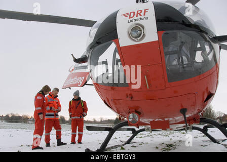 rescue helicopter standing in a snow-covered meadow before the start, Germany Stock Photo