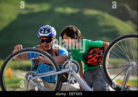 father and son repairing a bike, France, Savoie Stock Photo