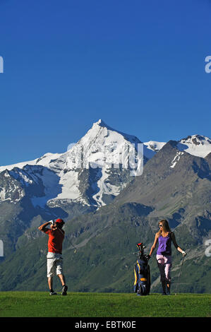 young couple playing golf, mont Pourri in background, France, Vanoise, Savoie Stock Photo
