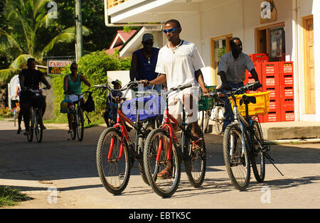 young man cycling and transporting in every hand another bike, Seychelles Stock Photo