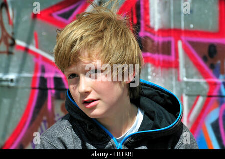 11 years old boy sitting in front of a graffiti wall Stock Photo