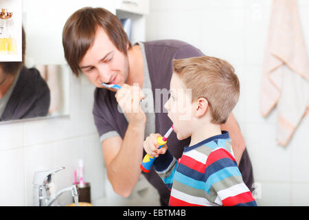 father and son brushing their teeth together Stock Photo