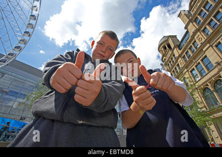 two young boys in the city centre raising their thumbs, United Kingdom, England, Manchester Stock Photo