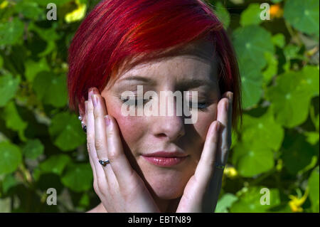 Young redhaired woman meditating in a green sweater against a purple ...