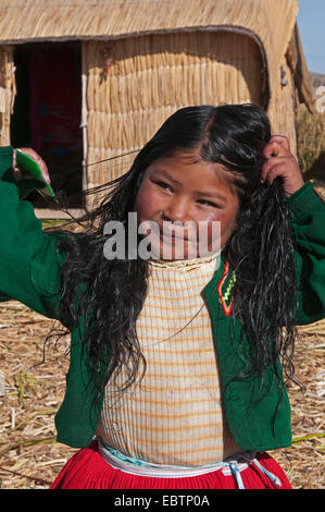 Quechua or Uros Indian girl on one of 42 floating islands on Lake Titicaca called 'Uros Islands', self-built of totora reeds, Peru, Uros Island, Lake Titicaca Stock Photo