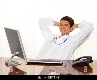 successful young manager sitting at a desk and smiles Stock Photo