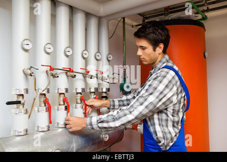 young heating engineer in the boiler room reading out the heating systems Stock Photo