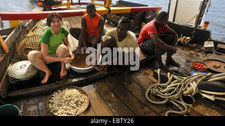 shelling prawns on the deck of a ship, Madagascar, Nosy be Stock Photo