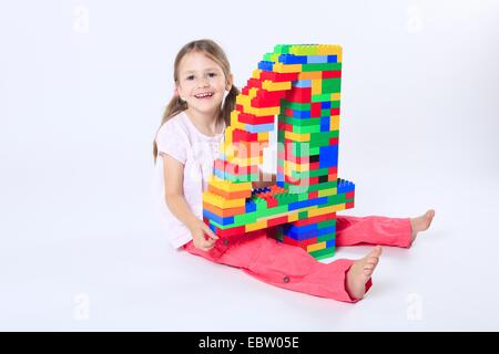 four-year-old girl with a large number '4' built of Lego bricks Stock Photo