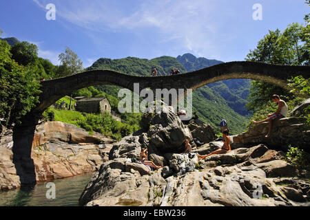 people sunbathing at Verzasca river at Ponte dei Salti at Lavertezzo, Switzerland, Ticino, Verzascatal Stock Photo