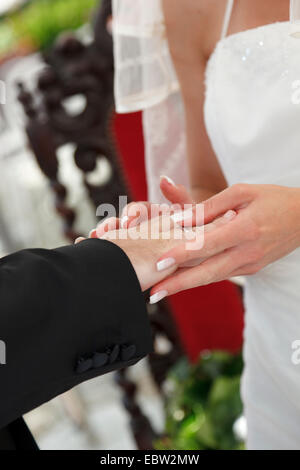 bride putting wedding ring on bridegoom's finger Stock Photo