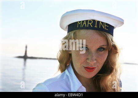 young redheaded woman with sailor cap at the sea, Germany, Mecklenburg-Western Pomerania Stock Photo