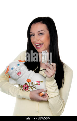 young darkhaired woman with piggy bank and banknote Stock Photo