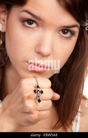 young brown-haired woman holding a cross in her hand Stock Photo