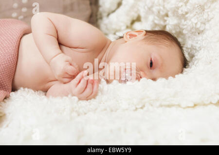baby with pacifier is tired in bed on a white blanket Stock Photo