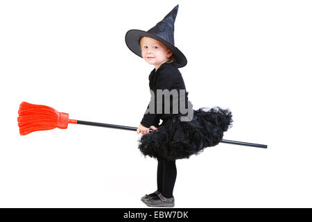 little girl in witch costume sitting back to front on a broom Stock Photo