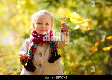 little girl with scarf holding autumn leaf Stock Photo