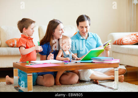 family with two children reading and painting in living room