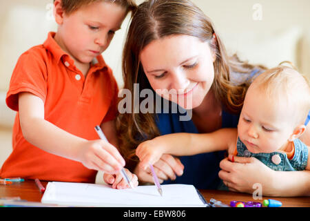 a young mother painting with her two children Stock Photo