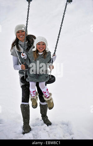 mother and daughter on seesaw in snow Stock Photo