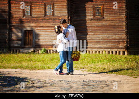 Young couple in Ukrainian style clothing going to kiss while standing on road in old village Stock Photo