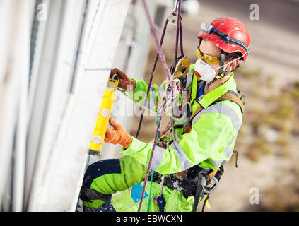 IIndustrial climber measuring with level tube during construction works Stock Photo