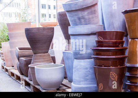 Glazed and unglazed ceramic flower pots in a variety of sizes and colors stacked on wooden pallets outside a pottery, warehouse Stock Photo