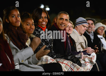 US President Barack Obama sits with First lady Michelle Obama and daughters Malia and Sasha during the lighting of the national Christmas tree during a ceremony on the Ellipse December 4, 2014 in Washington, DC. Obama urged Americans to remember members of the U.S. military serving overseas, as well as their families. This year's ceremony marks the 92nd annual lighting of the Christmas tree near the White House. The White House tree lighting is a tradition dating to 1923. Stock Photo