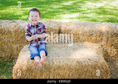 Cute Young Mixed Race Boy Having Fun on Hay Bale Outside.
