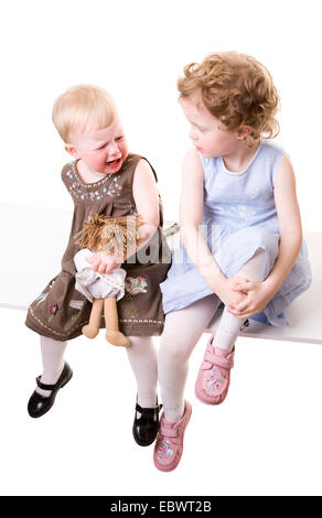 two little girls sitting on a bench disouting Stock Photo