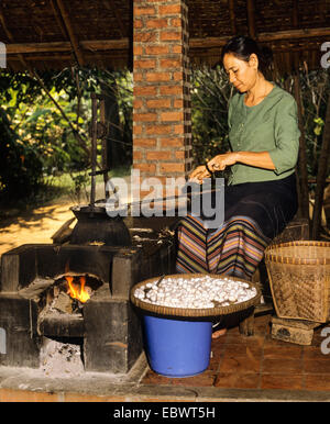 Silkworm cocoons in a silk factory, silk being removed and wound on a spindle, silk production, Chiang Mai, Northern Thailand Stock Photo
