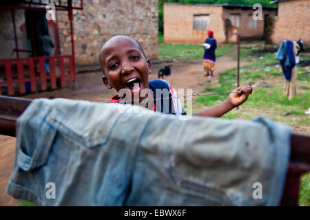 boy in a courtyard looking over a clothesline laughing, Burundi, Bujumbura Marie, Bujumbura Stock Photo