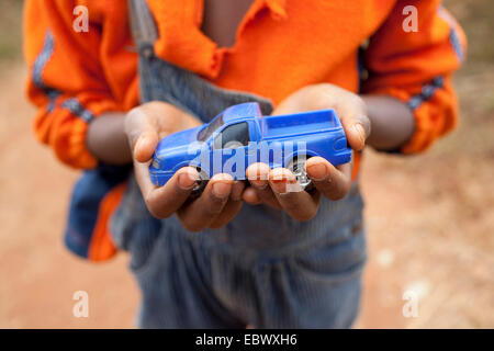 boy holding a blue toy car in his hands, Burundi, Karuzi, Buhiga Stock Photo
