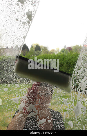 woman cleaning a window seen from inside Stock Photo