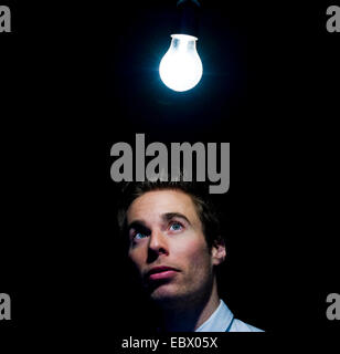 man looking at glowing light bulb Stock Photo