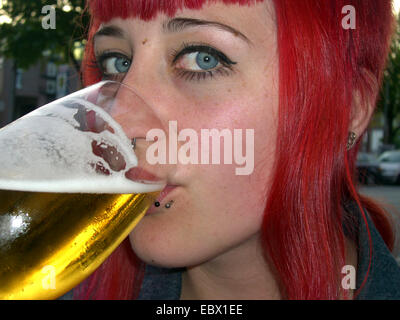 young redheaded woman drinking beer Stock Photo