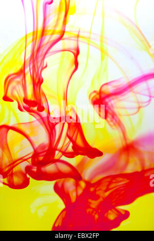 yellow and red color poured into water forming interesting streaks Stock Photo