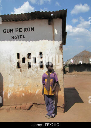 Refugee camp for internally displaced people in northern Uganda around Gulu, simple mud house in the background, boy standing next to a simple hotel, Uganda, Gulu Stock Photo
