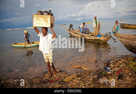 a boy carrying a box with oil lamps from fishing boat, Lake Tanganyika, Burundi, Makamba, Mvugo, Nyanza Lac Stock Photo
