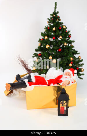 little boy dressed up as Santa Claus lying exhausted in a box, Switzerland Stock Photo