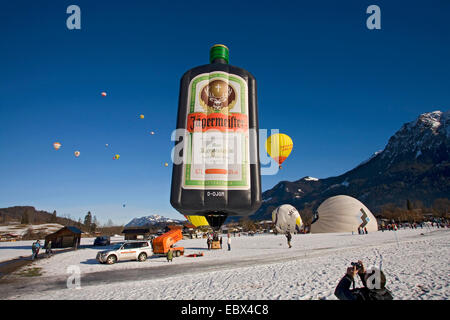 hot-air balloon festival on a snow field with several balloons being prepared for the start or having taken off and a lot of spectators, Germany, Bavaria, Allgaeu, Oberstdorf Stock Photo