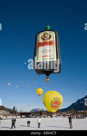 hot-air balloon festival on a snow field with several balloons being prepared for the start or having taken off and a lot of spectators, Germany, Bavaria, Allgaeu, Oberstdorf Stock Photo