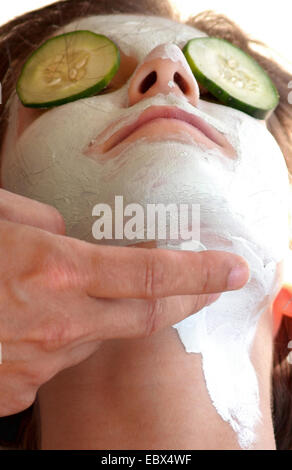 woman getting a face pack with cucumber slices on the eyes Stock Photo