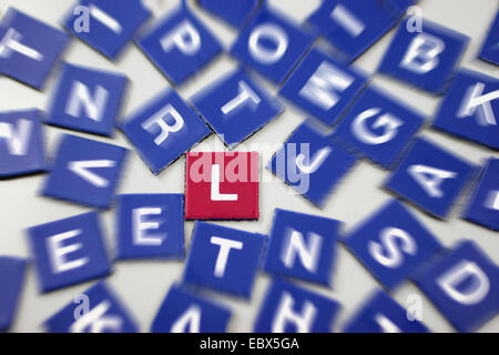 blue scrabble tokens with focus on one red L Stock Photo